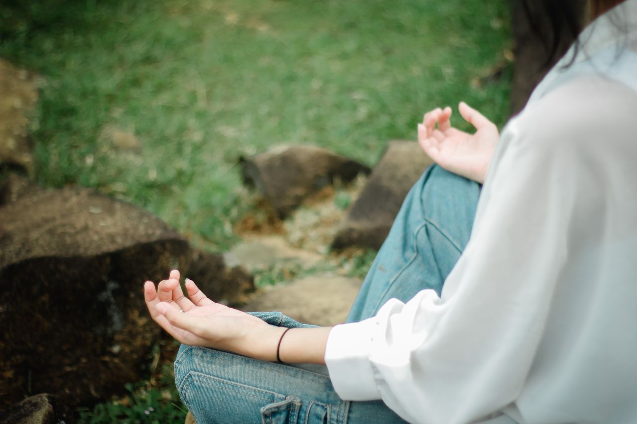 Home A person meditates outdoors, embracing tranquility and mindfulness.