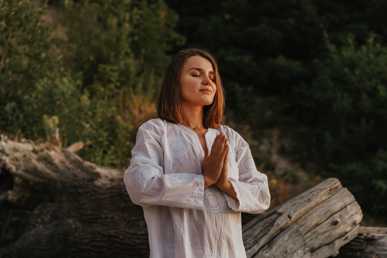 Home A woman with short hair meditates outdoors, embracing tranquility amidst nature.